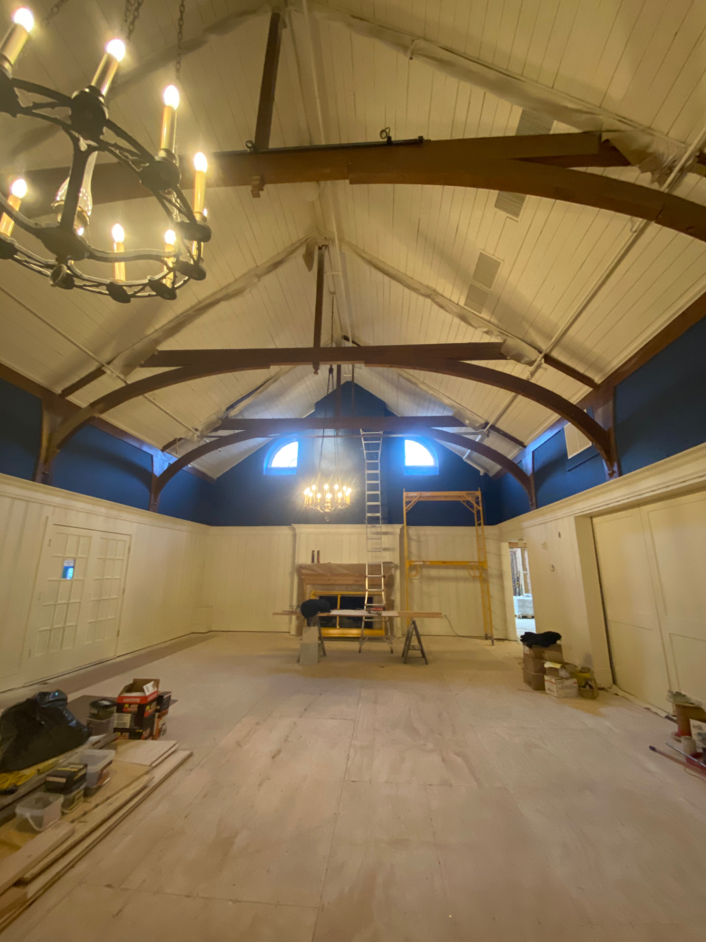 Large vaulted space with blue walls and white ceiling during painting