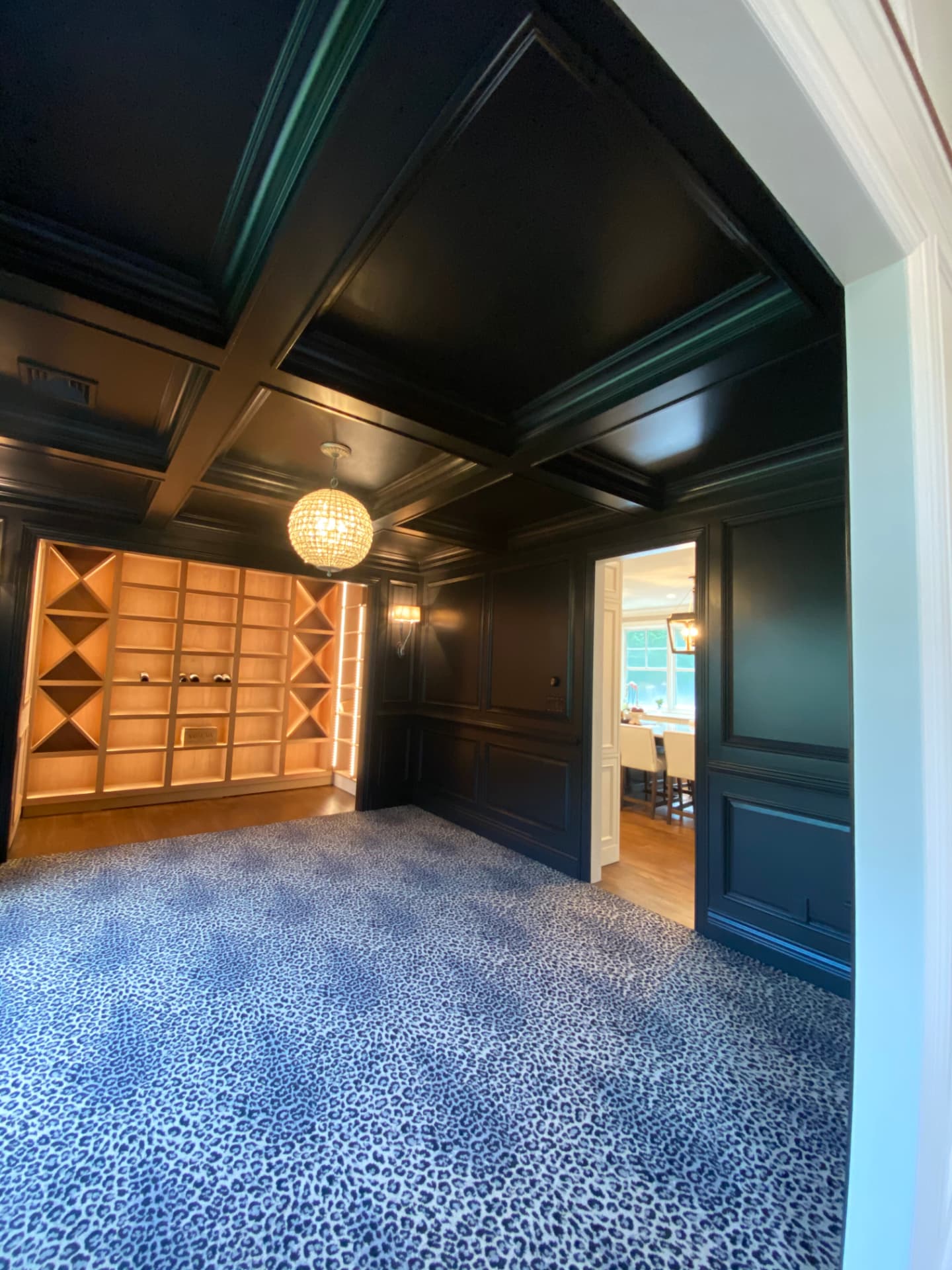 Dark architectural paneling and ceiling with softly illuminated wine shelves