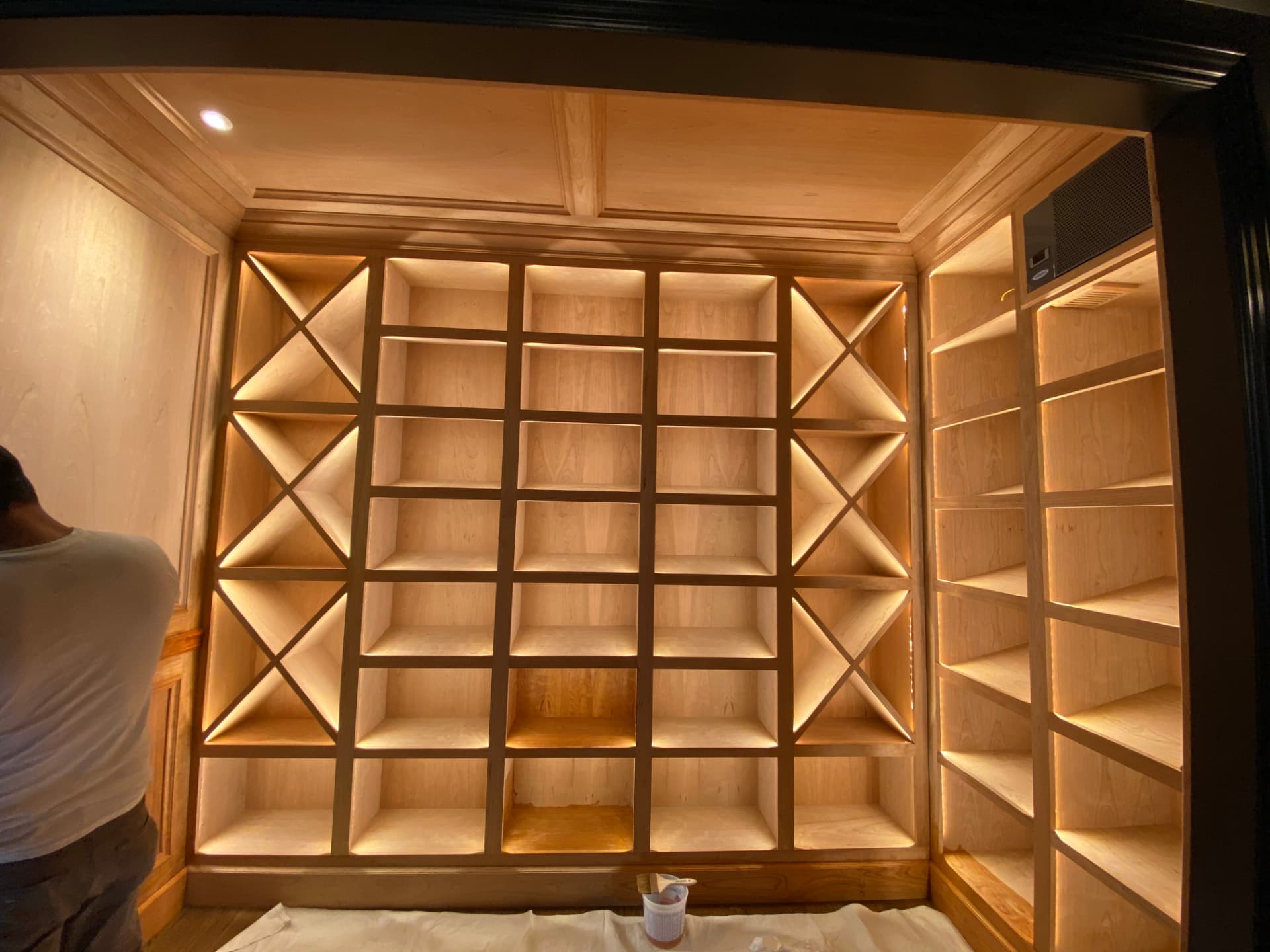 Warm integrated lighting across custom wine cabinets and display shelves