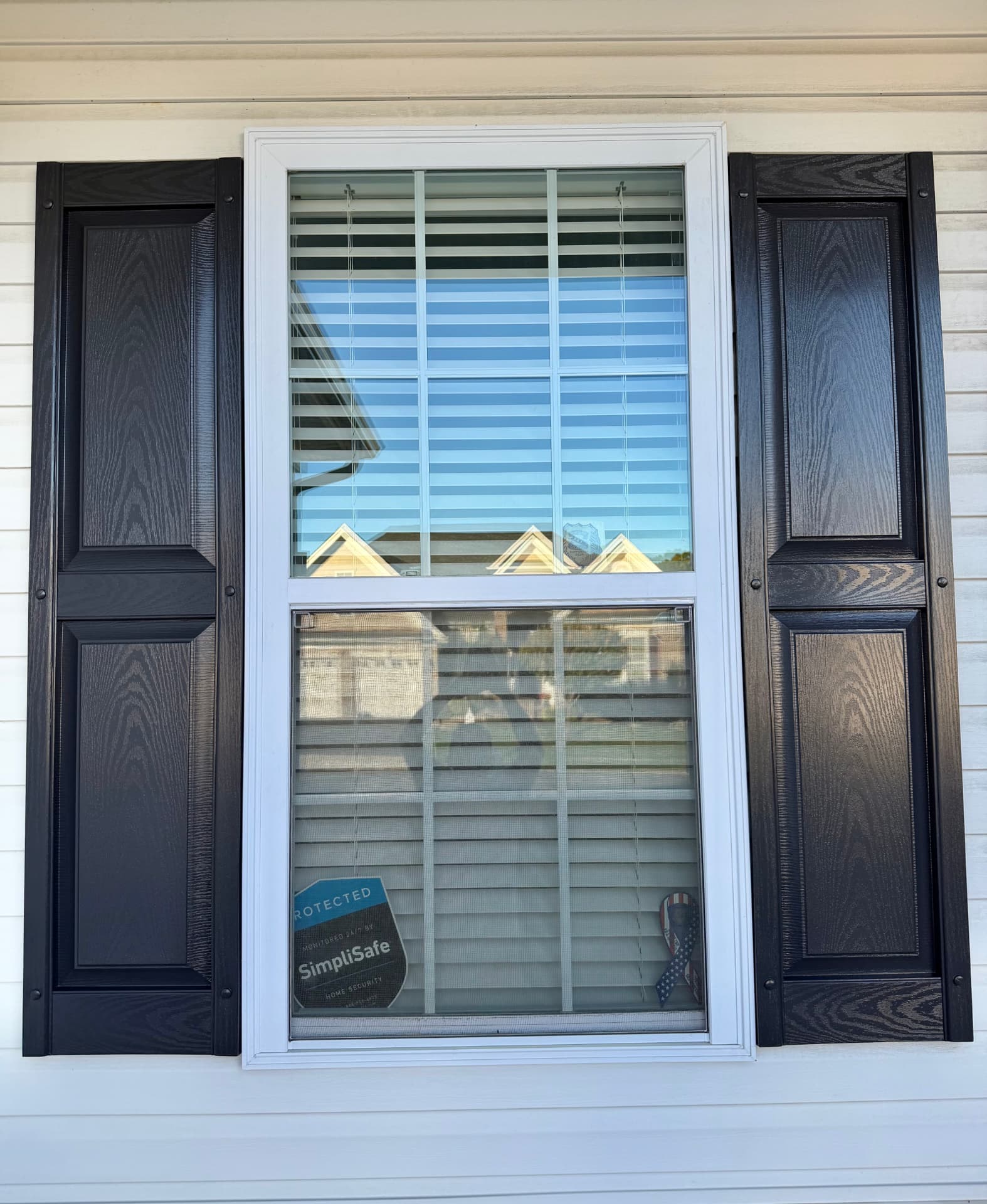 Finished dark window shutters with detailed panels and white window trim