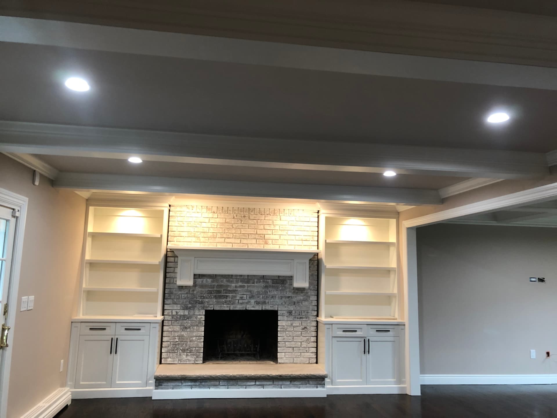 Living room built-ins with illuminated shelves, recessed lighting, and white cabinet finishes