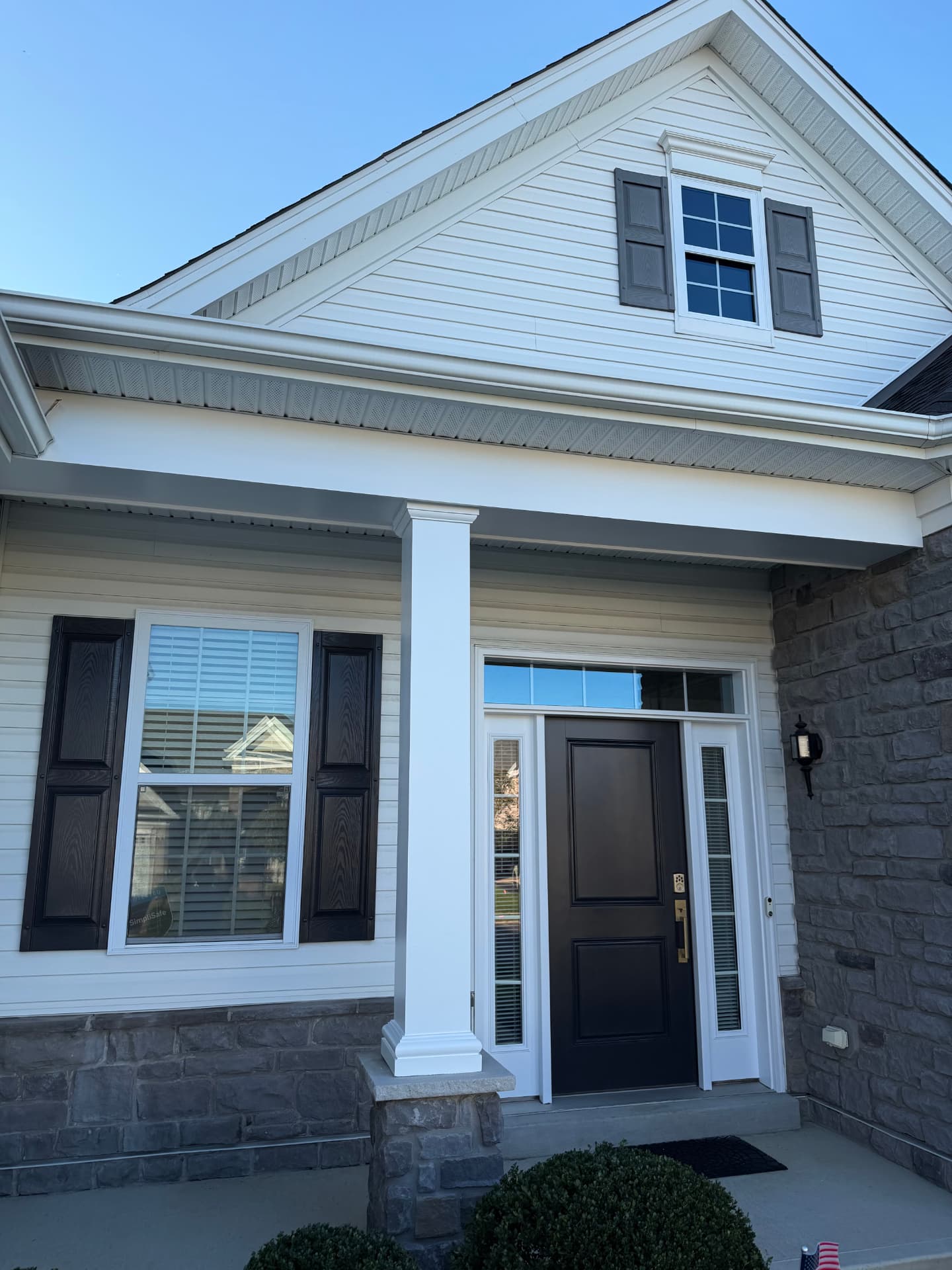 Finished porch with dark front door and shutters, white column, and fascia trim