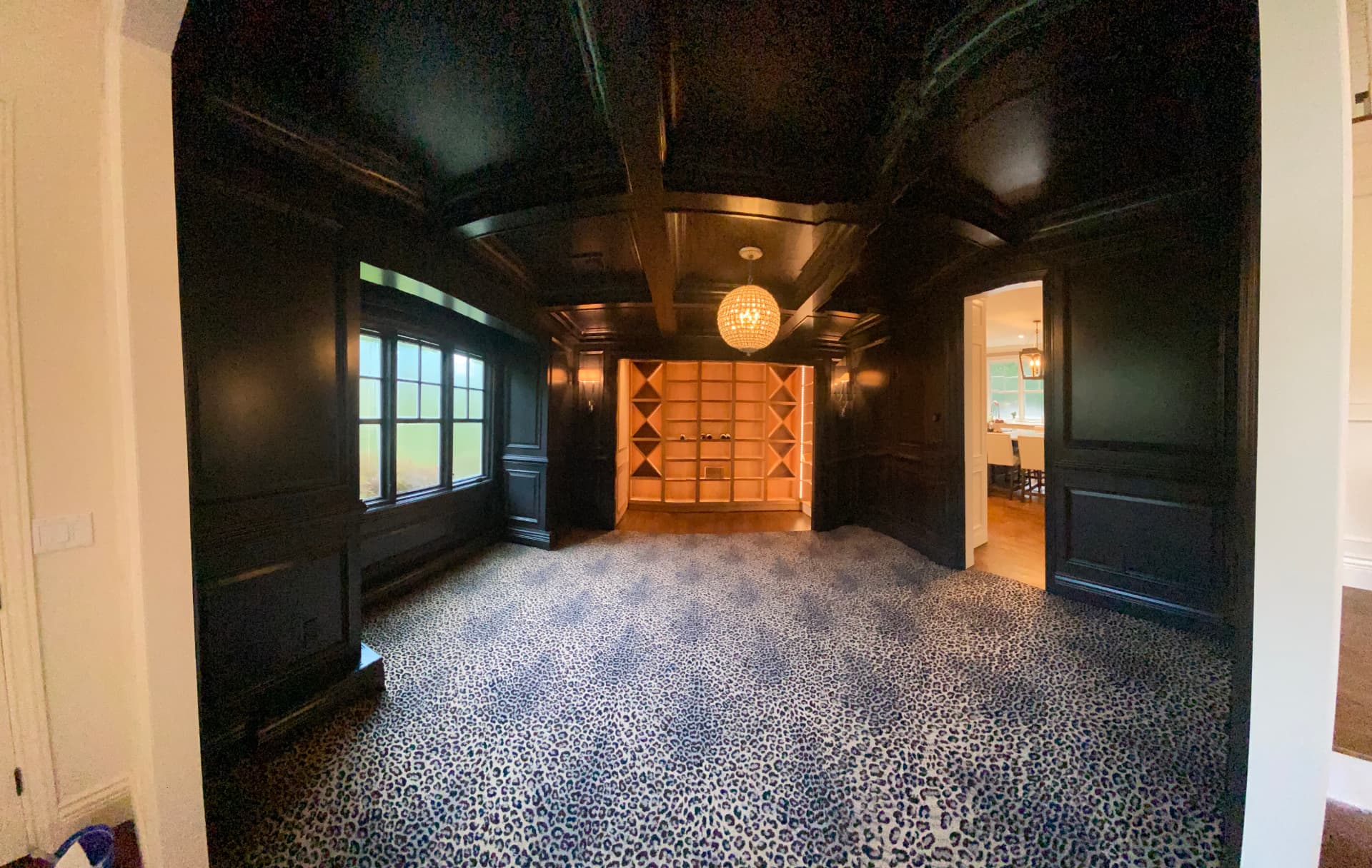 Dark painted room with coffered ceiling and illuminated wine display