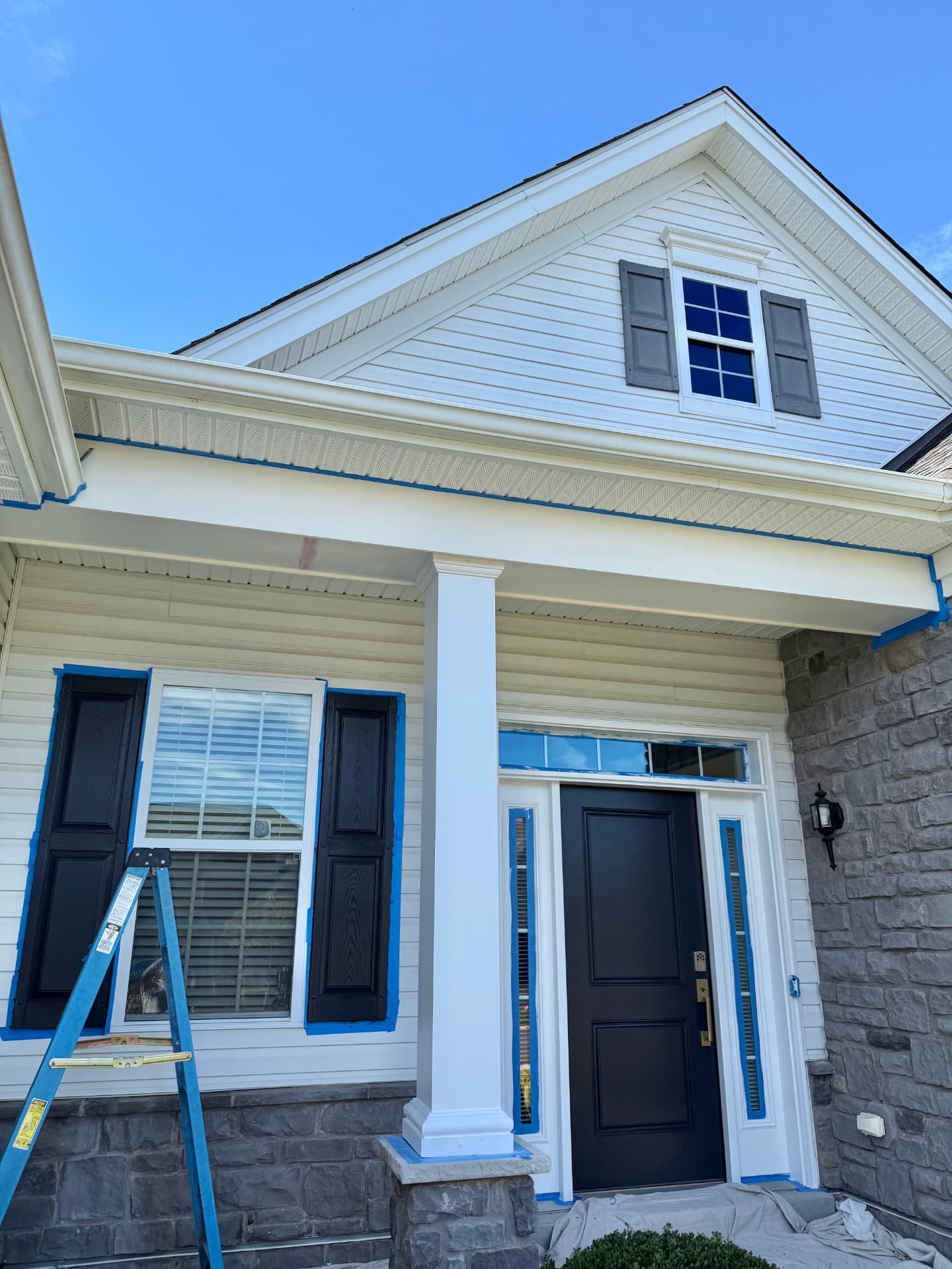 Porch painting in progress with masked shutters, entry trim, and white column