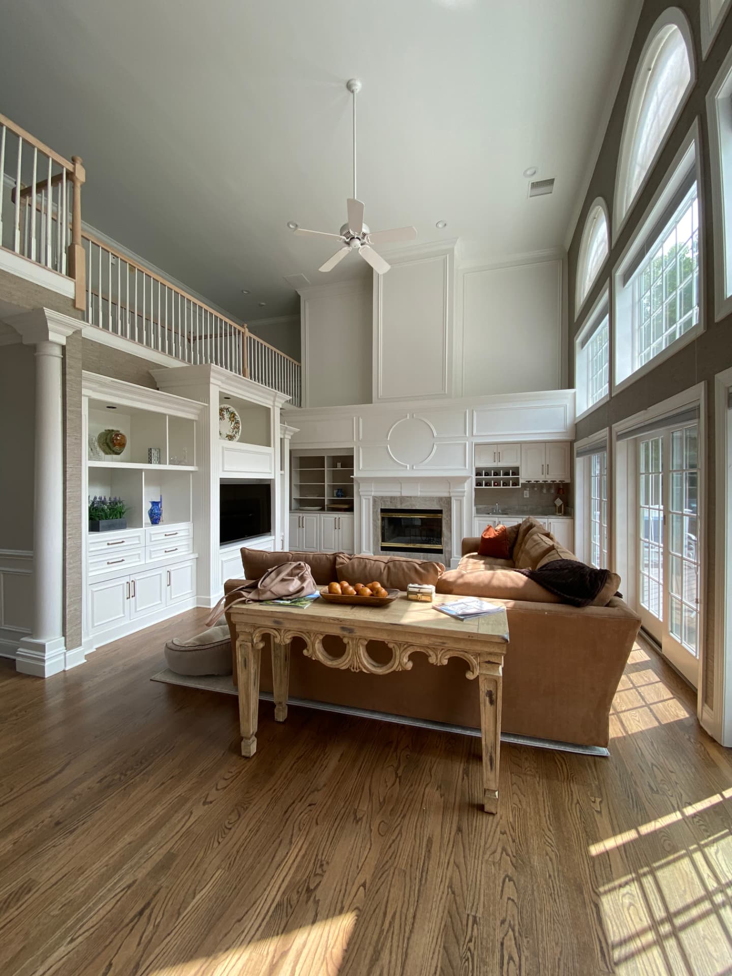 Double-height living room with white built-in cabinets and detailed fireplace trim